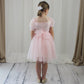 Light pink girls party dress featuring delicate Swiss dot tulle, short puff sleeves and a soft, flowing knee-length skirt.