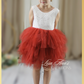 Flower girl dress in a rust tulle tiered skirt style. top bodice in a white lace sleeveless cut. 
